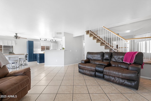 living room with visible vents, a ceiling fan, light tile patterned flooring, baseboards, and stairs