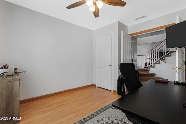 office area with baseboards, visible vents, light wood finished floors, and ceiling fan