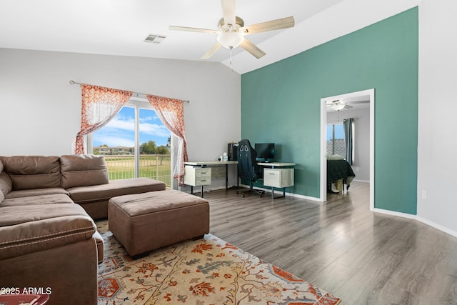 living area with wood finished floors, baseboards, a ceiling fan, visible vents, and vaulted ceiling