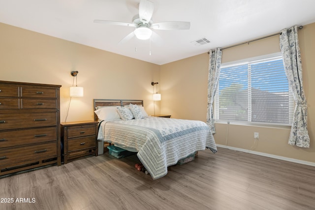 bedroom featuring visible vents, baseboards, light wood-style floors, and a ceiling fan