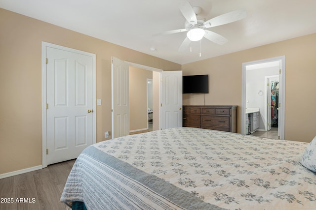 bedroom with a ceiling fan, ensuite bathroom, baseboards, and wood finished floors