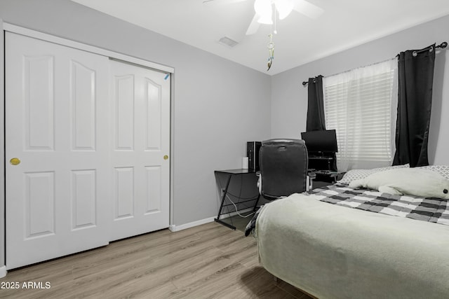 bedroom featuring a ceiling fan, visible vents, baseboards, light wood-style floors, and a closet