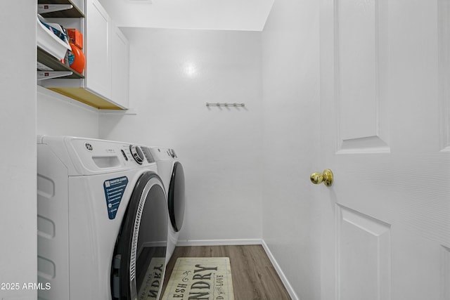 laundry area featuring cabinet space, wood finished floors, baseboards, and separate washer and dryer