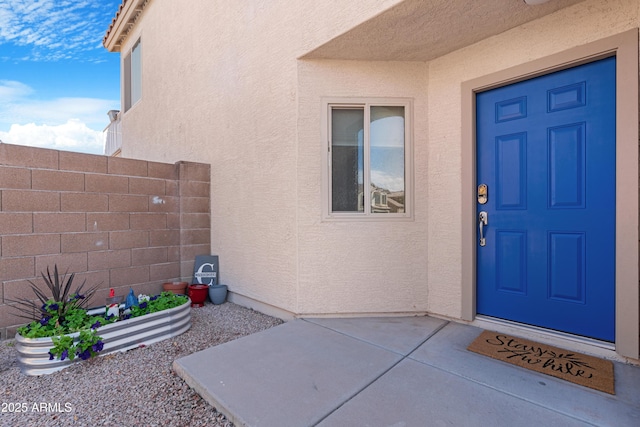 doorway to property with stucco siding and fence