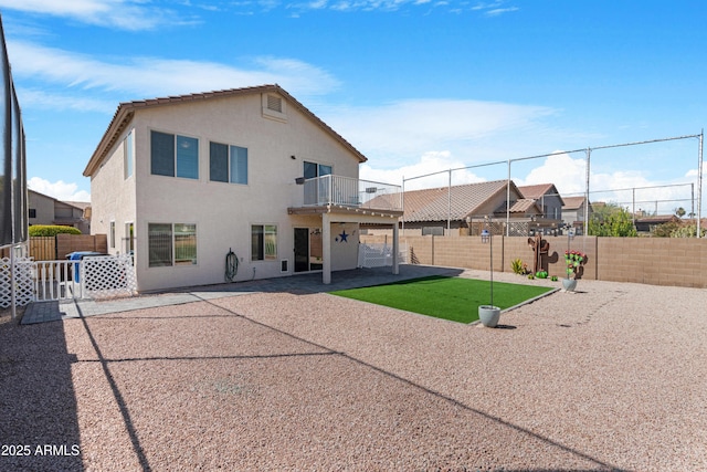 back of property featuring stucco siding, a patio, a balcony, and a fenced backyard