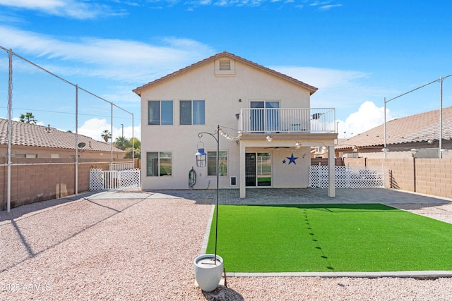 back of house featuring a balcony, a fenced backyard, and stucco siding