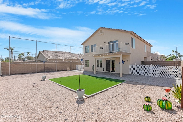 rear view of property with a fenced backyard, a patio area, stucco siding, and a balcony