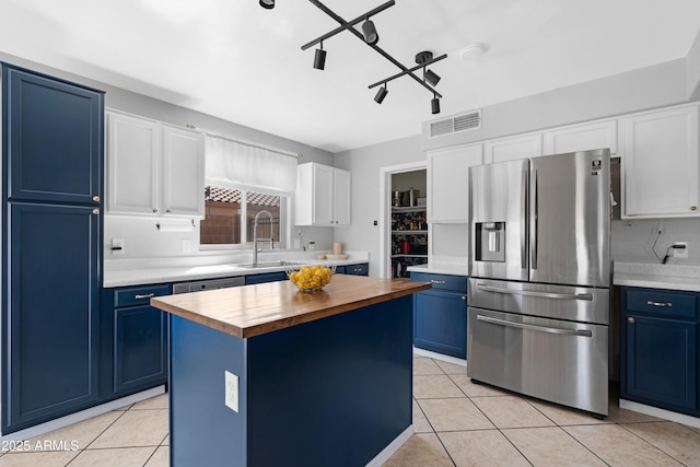 kitchen featuring blue cabinetry, stainless steel refrigerator with ice dispenser, and wood counters