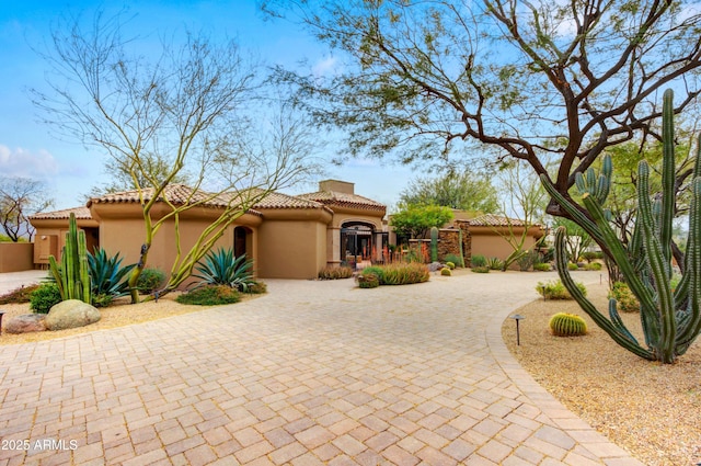 view of front of home featuring a tile roof, decorative driveway, and stucco siding