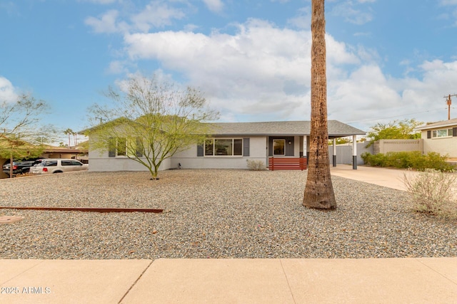 ranch-style home with an attached carport, fence, driveway, a shingled roof, and stucco siding