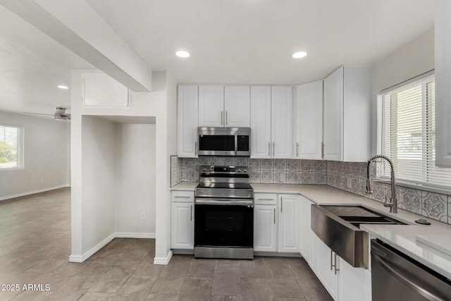 kitchen featuring backsplash, stainless steel appliances, light countertops, and a sink