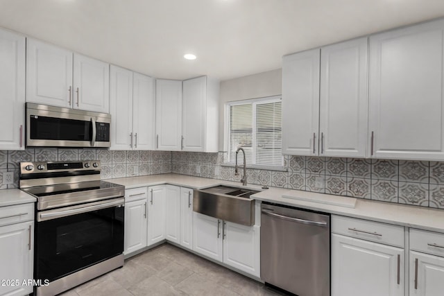 kitchen featuring backsplash, stainless steel appliances, light countertops, and a sink