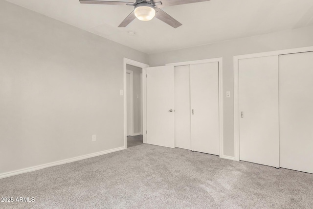 unfurnished bedroom featuring a ceiling fan, carpet, baseboards, and two closets