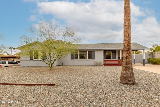 ranch-style house featuring a shingled roof, fence, stucco siding, a carport, and driveway