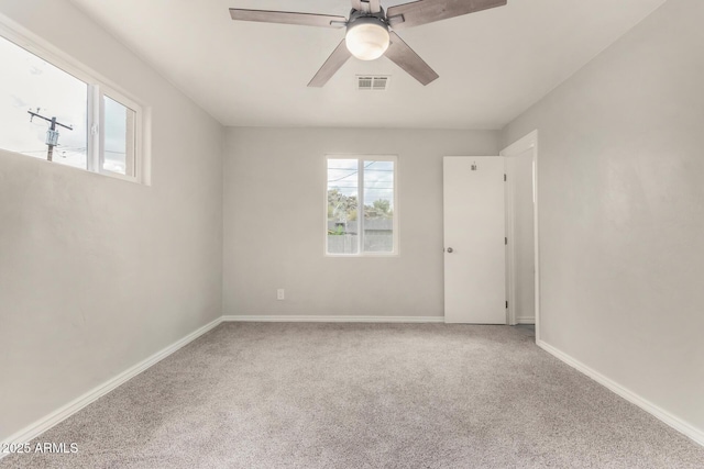 carpeted empty room with visible vents, baseboards, and ceiling fan