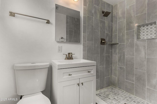 full bathroom with vanity, toilet, and a tile shower