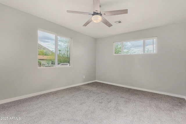 carpeted spare room featuring visible vents, baseboards, and a ceiling fan