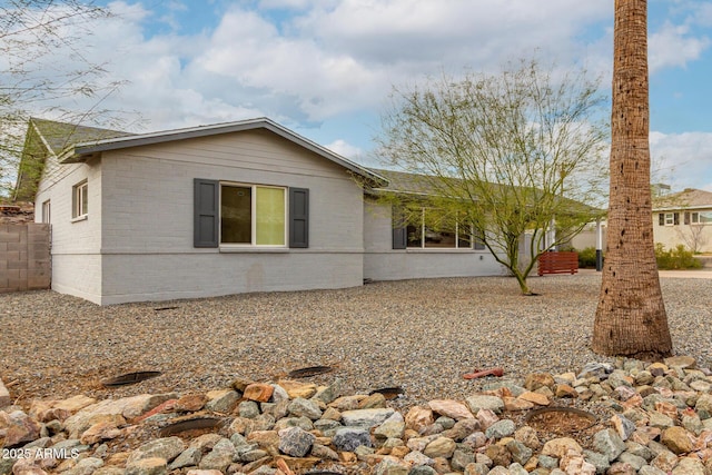 view of front of house featuring brick siding and fence