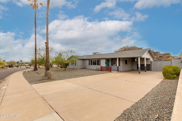 ranch-style home featuring fence, an attached carport, concrete driveway, and a gate