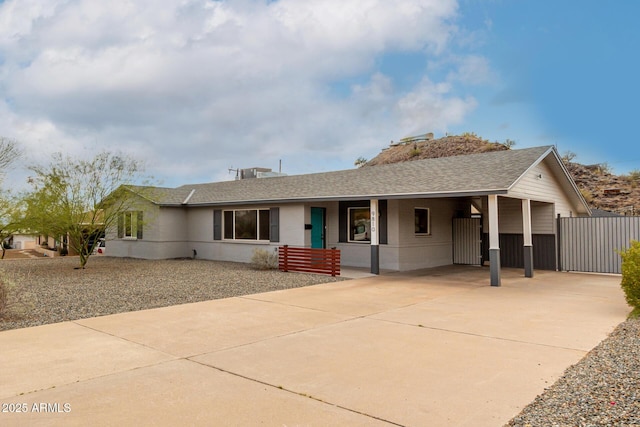 ranch-style home with a carport, concrete driveway, and a shingled roof