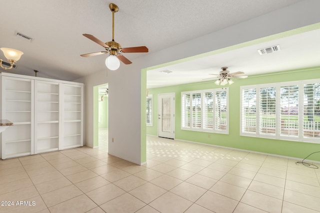 tiled empty room with ceiling fan, lofted ceiling, and a textured ceiling