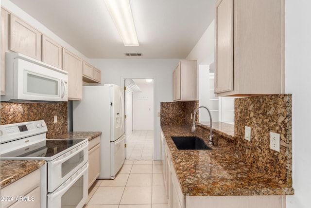 kitchen with sink, dark stone counters, white appliances, light brown cabinetry, and light tile patterned flooring