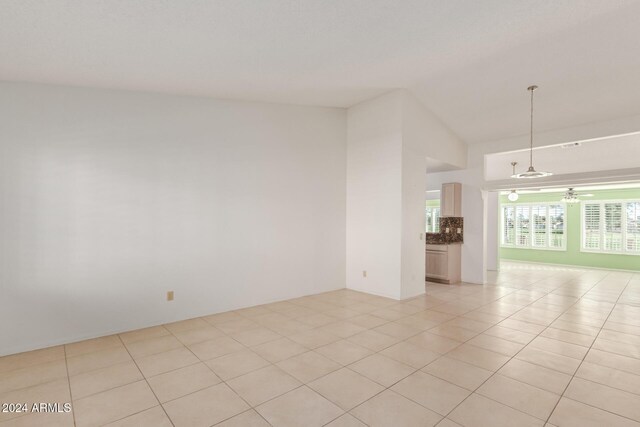 tiled empty room with ceiling fan and lofted ceiling