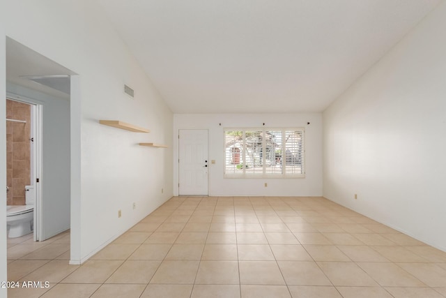 tiled spare room featuring vaulted ceiling