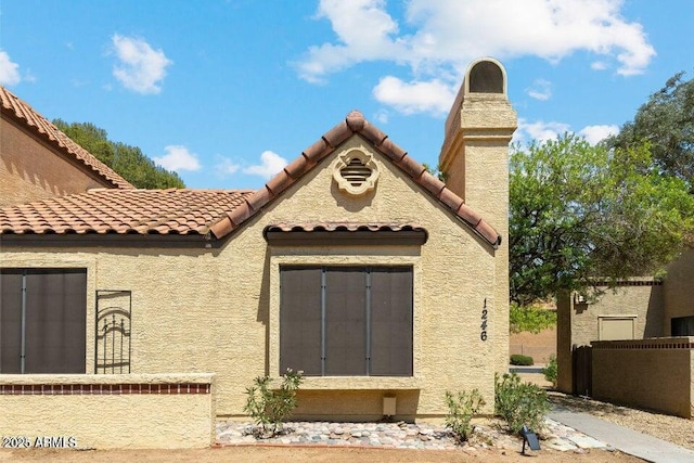 entrance to property with fence, stucco siding, and a tile roof