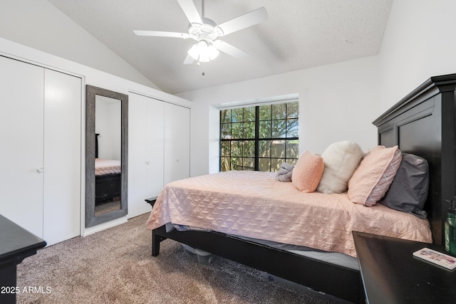 bedroom with vaulted ceiling, a ceiling fan, carpet, and two closets