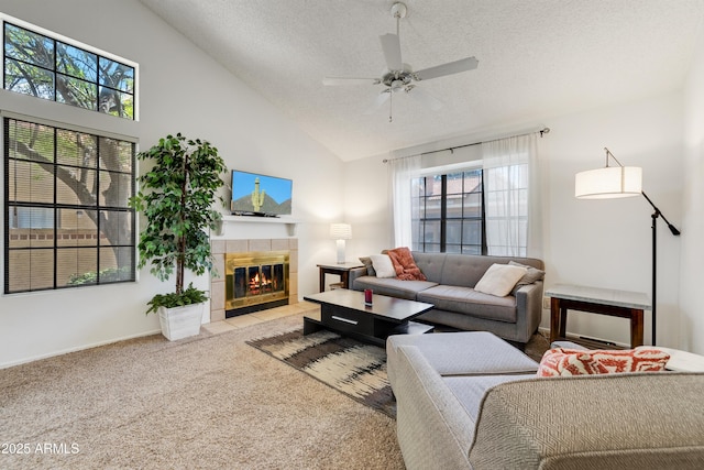 living area with carpet floors, a ceiling fan, a textured ceiling, and a tile fireplace