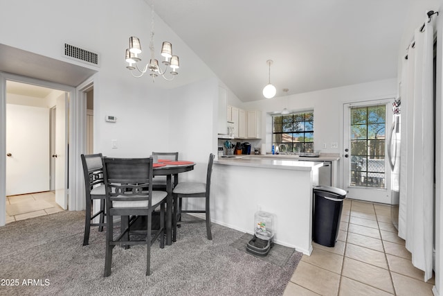 dining room featuring a notable chandelier, visible vents, light tile patterned floors, and lofted ceiling
