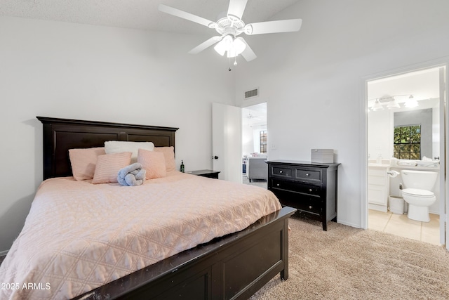 bedroom featuring a ceiling fan, light colored carpet, visible vents, high vaulted ceiling, and ensuite bath