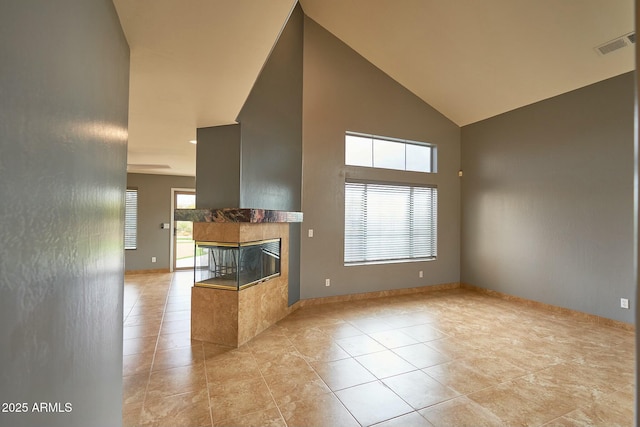 unfurnished living room with high vaulted ceiling, light tile patterned flooring, visible vents, baseboards, and a tiled fireplace