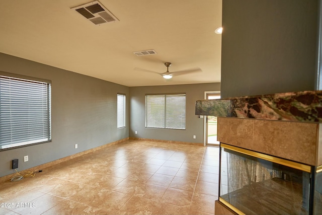 tiled empty room with baseboards, visible vents, and a ceiling fan