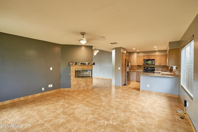 kitchen featuring tasteful backsplash, range, a premium fireplace, black microwave, and stainless steel refrigerator with ice dispenser