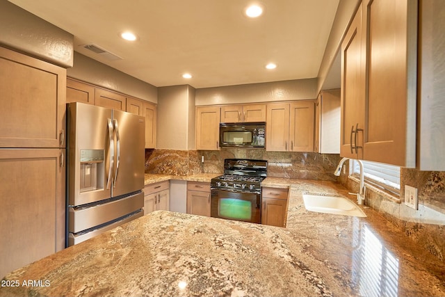 kitchen with visible vents, decorative backsplash, light stone counters, black appliances, and a sink