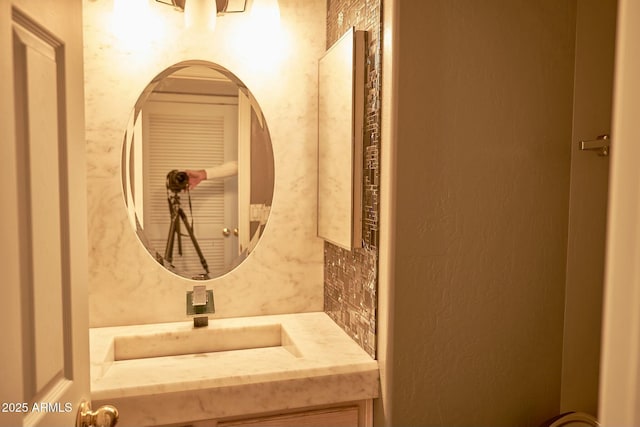 bathroom featuring vanity, backsplash, and a textured wall