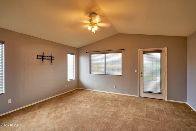 carpeted spare room featuring baseboards and vaulted ceiling