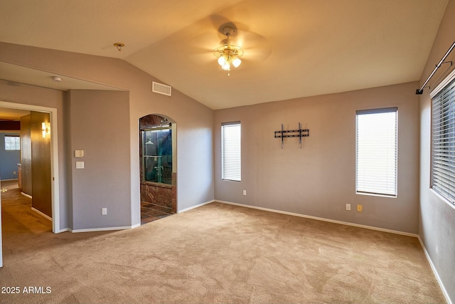 carpeted empty room featuring lofted ceiling, visible vents, and baseboards