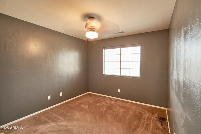 unfurnished room with carpet floors, visible vents, a textured wall, and baseboards