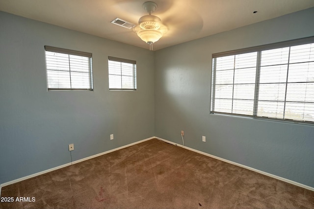 spare room with carpet flooring, ceiling fan, visible vents, and baseboards