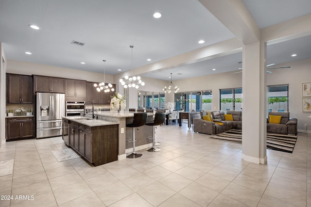 kitchen featuring light stone counters, pendant lighting, stainless steel fridge, and a notable chandelier