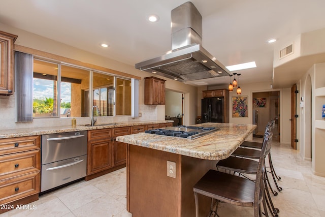 kitchen with stainless steel gas cooktop, a kitchen island, black fridge with ice dispenser, brown cabinetry, and island exhaust hood