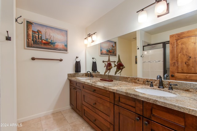 bathroom with double vanity, a stall shower, baseboards, and a sink