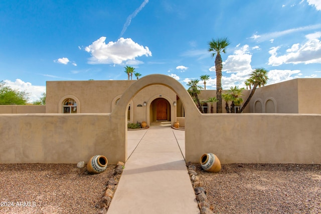 pueblo-style house with a fenced front yard and stucco siding