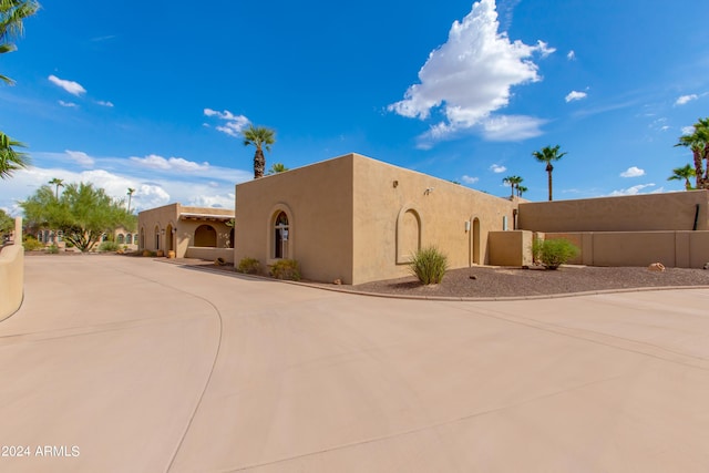 pueblo revival-style home with fence and stucco siding