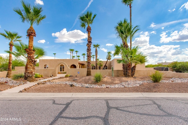 pueblo-style home with a fenced front yard and stucco siding