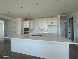 kitchen featuring white cabinetry, dark wood-type flooring, and a large island with sink