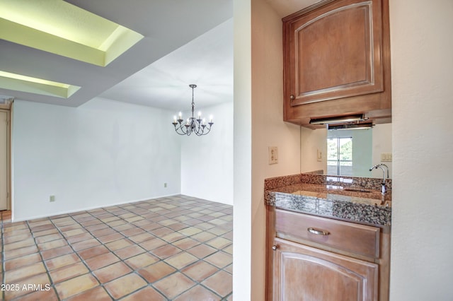 kitchen featuring an inviting chandelier, tile countertops, light tile patterned floors, and a sink